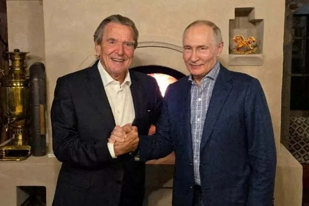 Президент России Владимир Путин пожимает руку бывшему канцлеру Германии Герхарду Шредеру